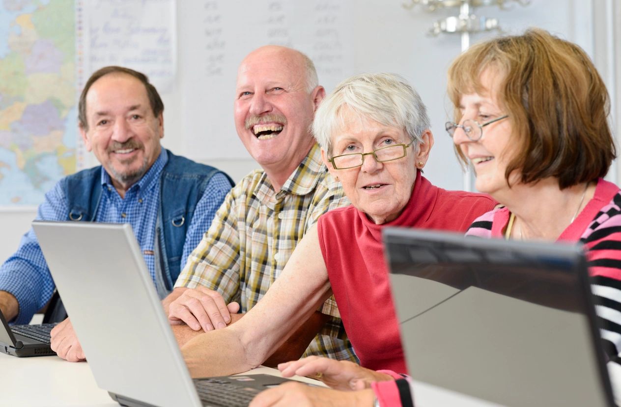 A group of people sitting around a table with laptops.